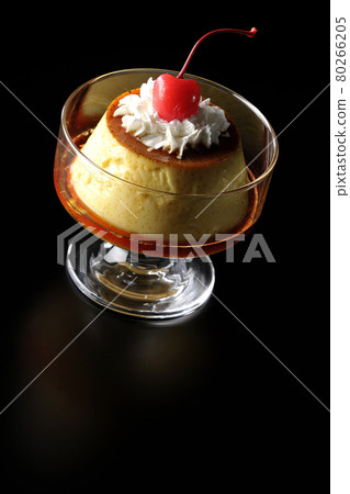Photographed custard pudding with vanilla beans with whipped cream and cherries on a black background Photographed custard pudding with vanilla beans with whipped cream and cherries on a black background 80266205