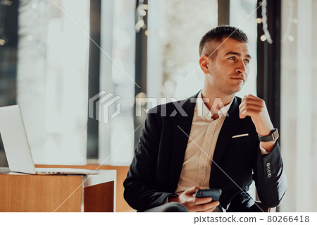 Happy business man sitting at cafeteria with laptop and smartphone Happy business man sitting at cafeteria with laptop and smartphone 80266418