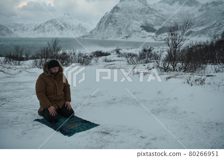 Muslim traveler praying in cold snowy winter day 80266951