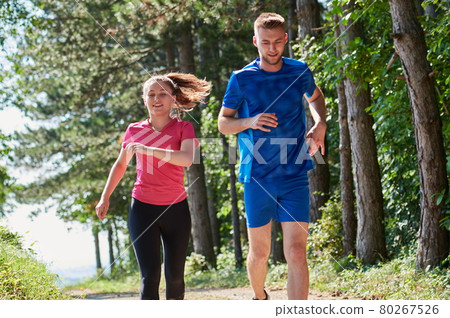 couple enjoying in a healthy lifestyle while jogging on a country road couple enjoying in a healthy lifestyle while jogging on a country road 80267526