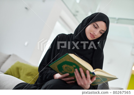 Portrait of young muslim woman reading Quran in modern home Portrait of young muslim woman reading Quran in modern home 80267565
