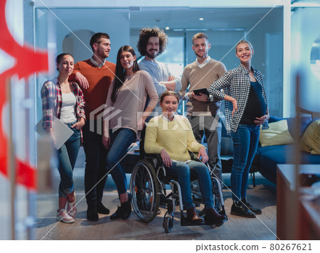 Disabled businesswoman in a wheelchair at the office with coworkers team 80267621