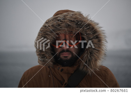 man at winter in stormy weather wearing warm fur jacket 80267681