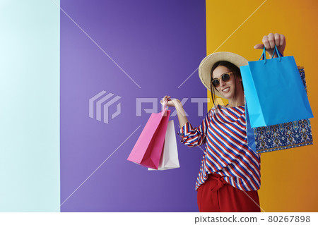 Young woman with shopping bags on colorful background 80267898