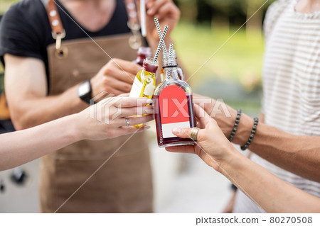 People clinking bottles with a strong alcohol drinks outdoors People clinking bottles with a strong alcohol drinks outdoors 80270508