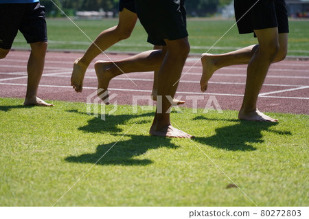 Runner running barefoot on the grass 80272803