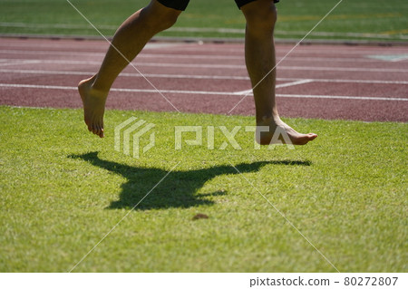 Runner running barefoot on the grass 80272807