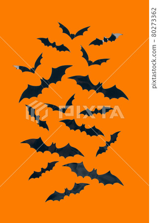Halloween background - decorative paper bats on orange background with copy space. Halloween decorations or party invitation concept. Selective focus, vertical image 80273362