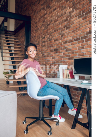 Young african american woman sitting at the table at her working place Young african american woman sitting at the table at her working place 80273705