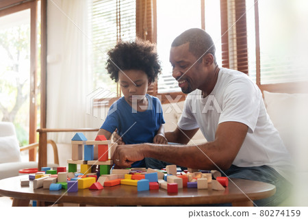 Brazilian Father and his Little son playing building tower from wooden block toy on sofa 80274159