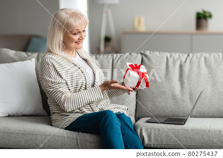 Smiling Mature Woman Holding Present Gift Box Making Video Call Smiling Mature Woman Holding Present Gift Box Making Video Call 80275437