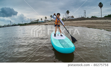 A cute elementary school child playing SUP board in the summer sea 80275758