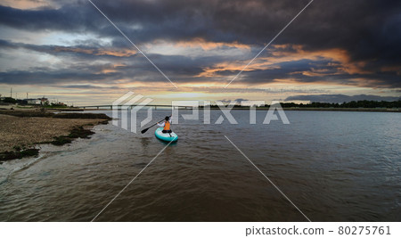 A cute elementary school child playing SUP board in the summer sea and a beautiful sunset scenery A cute elementary school child playing SUP board in the summer sea and a beautiful sunset scenery 80275761