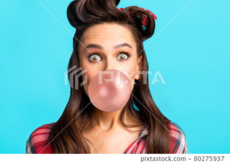 Emotional young pin up woman in retro clothes blowing bubble from chewing gum over blue studio background 80275937