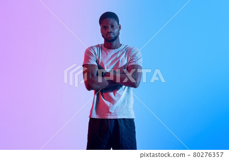 Black male fitness model standing with crossed arms, looking at camera in neon light 80276357