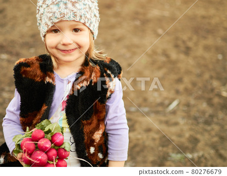A happy little girl holds a bunch of freshly harvested radishes in her hands. 80276679