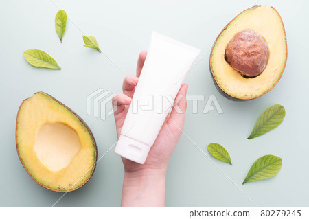 Natural avocado skincare products for healthy skin and hair. Woman hand holding blank white squeeze tube with fresh organic avocado on green background. Beauty herbal skincare and haircare concept. Natural avocado skincare products for healthy skin and hair. Woman hand holding blank white squeeze tube with fresh organic avocado on green background. Beauty herbal skincare and haircare concept. 80279245