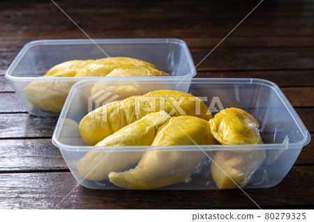 Golden yellow musang king durian pulp flesh in two containers on wooden surface 80279325
