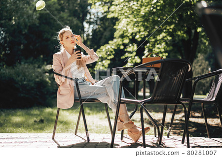 Beautiful young businesswoman drinking coffee in outdoor cafe Beautiful young businesswoman drinking coffee in outdoor cafe 80281007