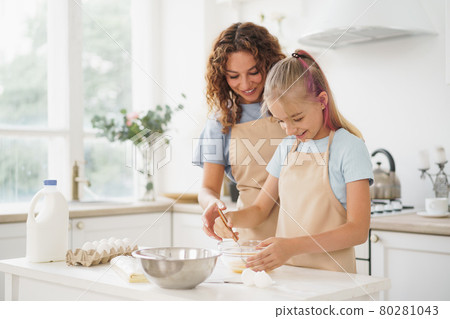 Mother and teen daughter making dough for pastry toghether in kitchen Mother and teen daughter making dough for pastry toghether in kitchen 80281043
