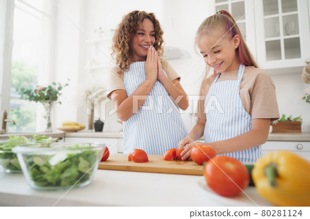 Mommy teaching her teen daughter to cook vegetable salad in kitchen Mommy teaching her teen daughter to cook vegetable salad in kitchen 80281124