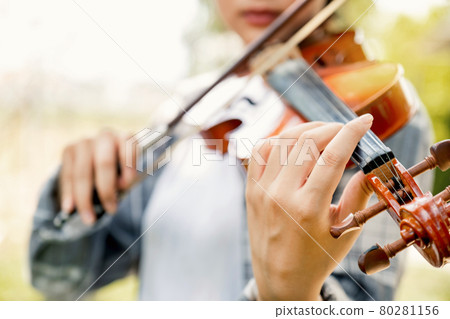 Close-up portrait of Young Asia woman music violinist hand play violin, relax in the garden with peace of mind Close-up portrait of Young Asia woman music violinist hand play violin, relax in the garden with peace of mind 80281156