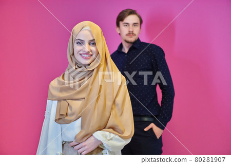 Portrait of happy young muslim couple standing isolated on pink background 80281907