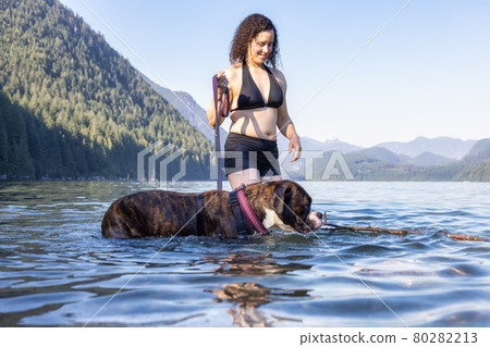 Caucasian Woman swimming in a lake with dog 80282213