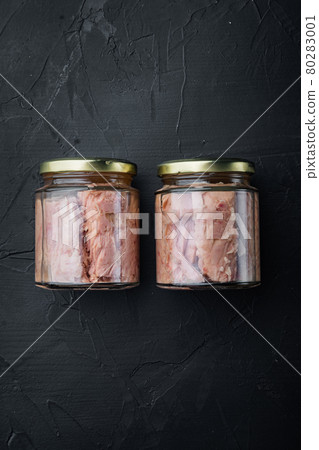 Jar of tuna in olive oil, on black background, top view with copy space for text 80283001