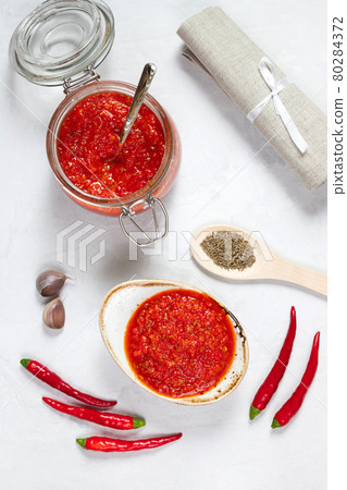 Hot chili pepper sauce paste harissa. Adjika on a white background. Traditional Tunisia, Georgian and Arabic cuisine. Homemade rose harissa in a bowl. 80284372