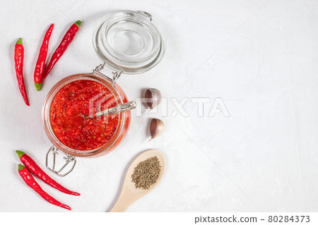 Hot chili pepper sauce paste harissa. Adjika. Traditional Tunisia, Georgian and Arabic cuisine. Homemade rose harissa in a glass jar. 80284373