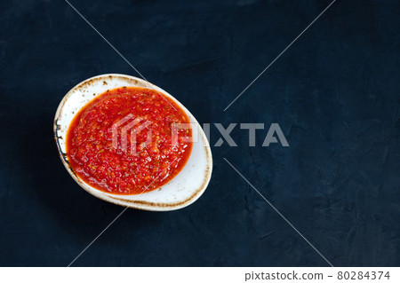Hot chili pepper sauce paste harissa. Adjika. Traditional Tunisia, Georgian and Arabic cuisine. Homemade rose harissa in a bowl. 80284374