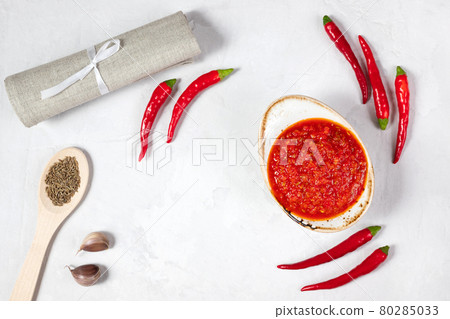 Hot chili pepper sauce paste harissa. Adjika on a white background. Traditional Tunisia, Georgian and Arabic cuisine. Homemade rose harissa in a bowl. Hot chili pepper sauce paste harissa. Adjika on a white background. Traditional Tunisia, Georgian and Arabic cuisine. Homemade rose harissa in a bowl. 80285033