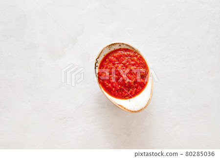 Hot chili pepper sauce paste harissa. Adjika on a white background. Traditional Tunisia, Georgian and Arabic cuisine. Homemade rose harissa in a bowl. Hot chili pepper sauce paste harissa. Adjika on a white background. Traditional Tunisia, Georgian and Arabic cuisine. Homemade rose harissa in a bowl. 80285036