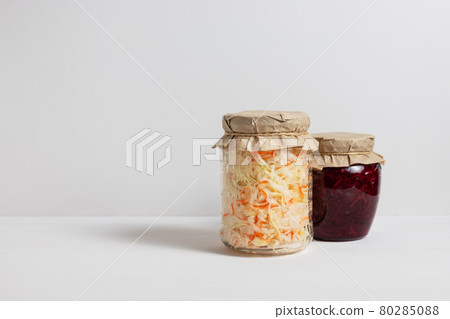 Homemade sauerkraut with carrots and cabbage salad with beets in a glass jar on a white wooden background. Fermented food. Copy space Homemade sauerkraut with carrots and cabbage salad with beets in a glass jar on a white wooden background. Fermented food. Copy space 80285088