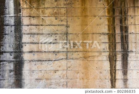 A weathered, concrete wall is part of a railway bridge.  80286835