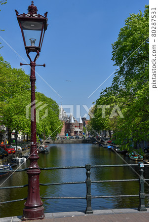 Amsterdam, the Netherlands. April 2020. Bridge over a canal with view at the Waag. 80287531