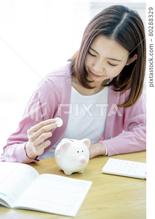 A woman who puts money in a piggy bank 80288329