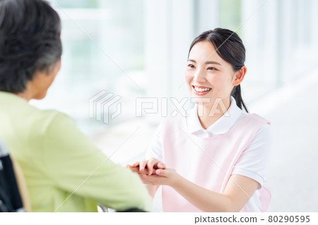 Young care staff woman talking to a senior woman in a wheelchair 80290595