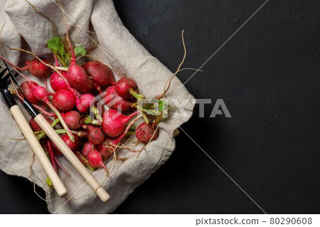 Red radishes in a box, with gardening tools. Harvesting. On a black background, with space, top view 80290608