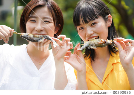 A woman eating salt-grilled sweetfish 80290986