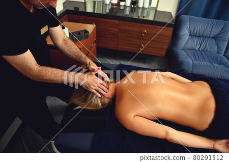 Top view of physiotherapist giving neck massage to woman lying on massage table in wellness center 80291512