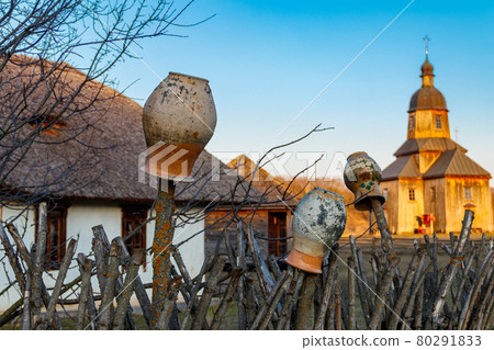 Old clay jugs on a wooden fence in a village in Ukraine. Traditional ukrainian rural decor Old clay jugs on a wooden fence in a village in Ukraine. Traditional ukrainian rural decor 80291833
