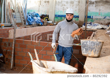 Bricklayer installing brick wall 80292392