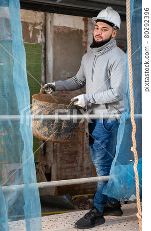 Contractor carrying bucket with cement mortar Contractor carrying bucket with cement mortar 80292396