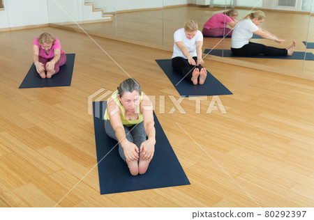 Women are doing seating forward bend 80292397
