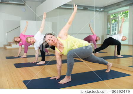 Active senior women practicing twisting yoga poses 80292479