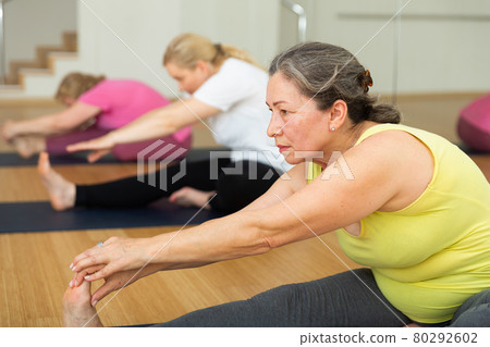 Women are doing head-to-knee pose 80292602