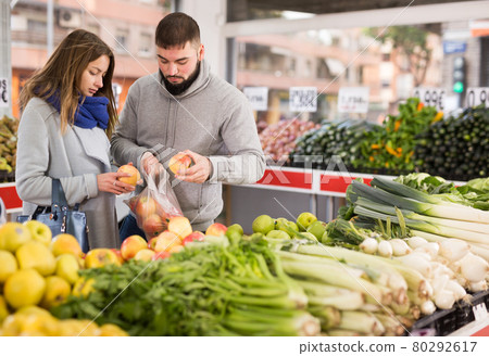 Friendly couple examining apples in grocery shop Friendly couple examining apples in grocery shop 80292617