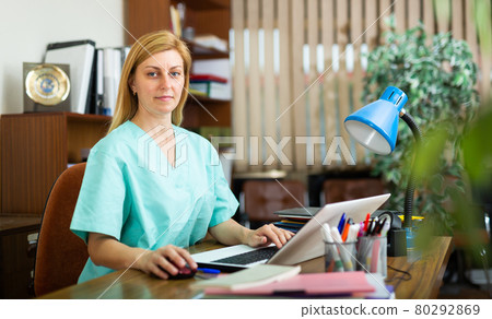 Woman doctor sitting at workplace with computer in office Woman doctor sitting at workplace with computer in office 80292869